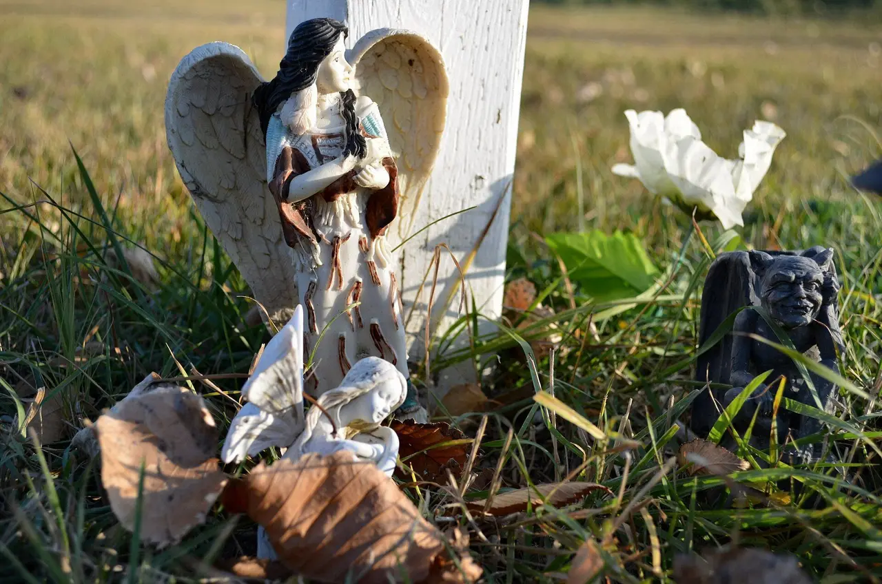 Angel and gargoyle figurines at a grave marker, 2011